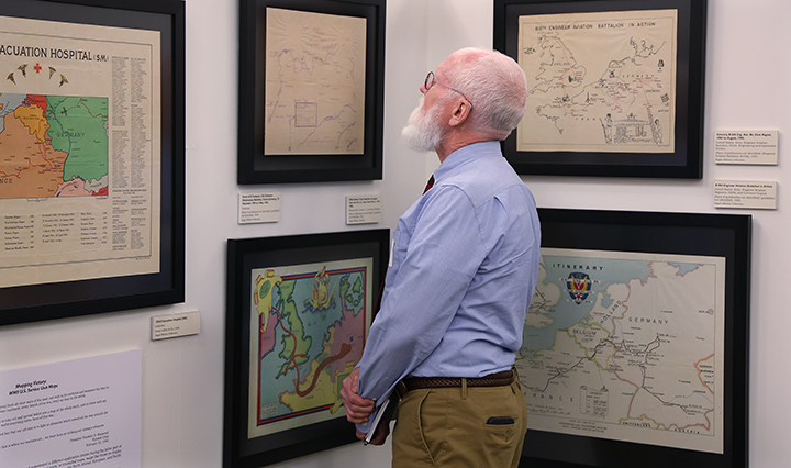 man looking at framed maps