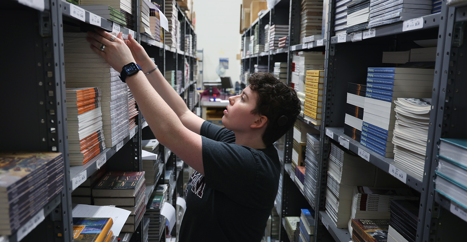 worker organizing books on shelves