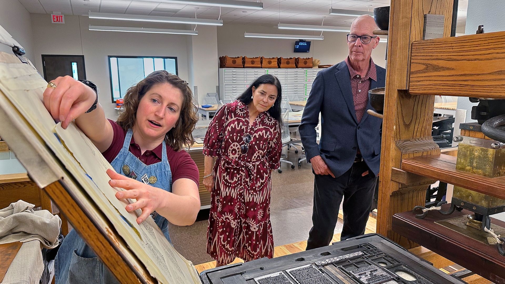 Maddie Keyser, Texas A&M University's book arts and historic press room librarian, shows a period accurate common press in the Sterling C. Evans Library Annex to Dr. Diana Gabaldon and her husband, Doug Watkins. 