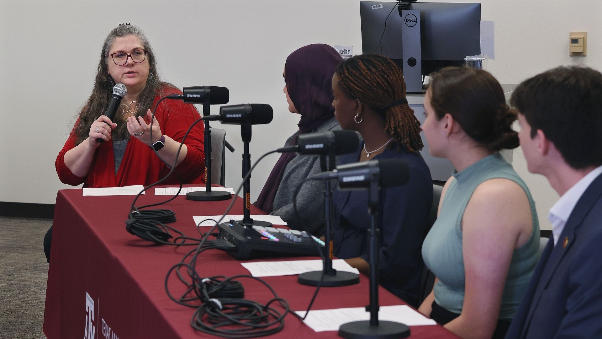 A table full of panelists in front of microphones. 4 are students and 1 is a library employee, for a total of 5 panel speakers. 