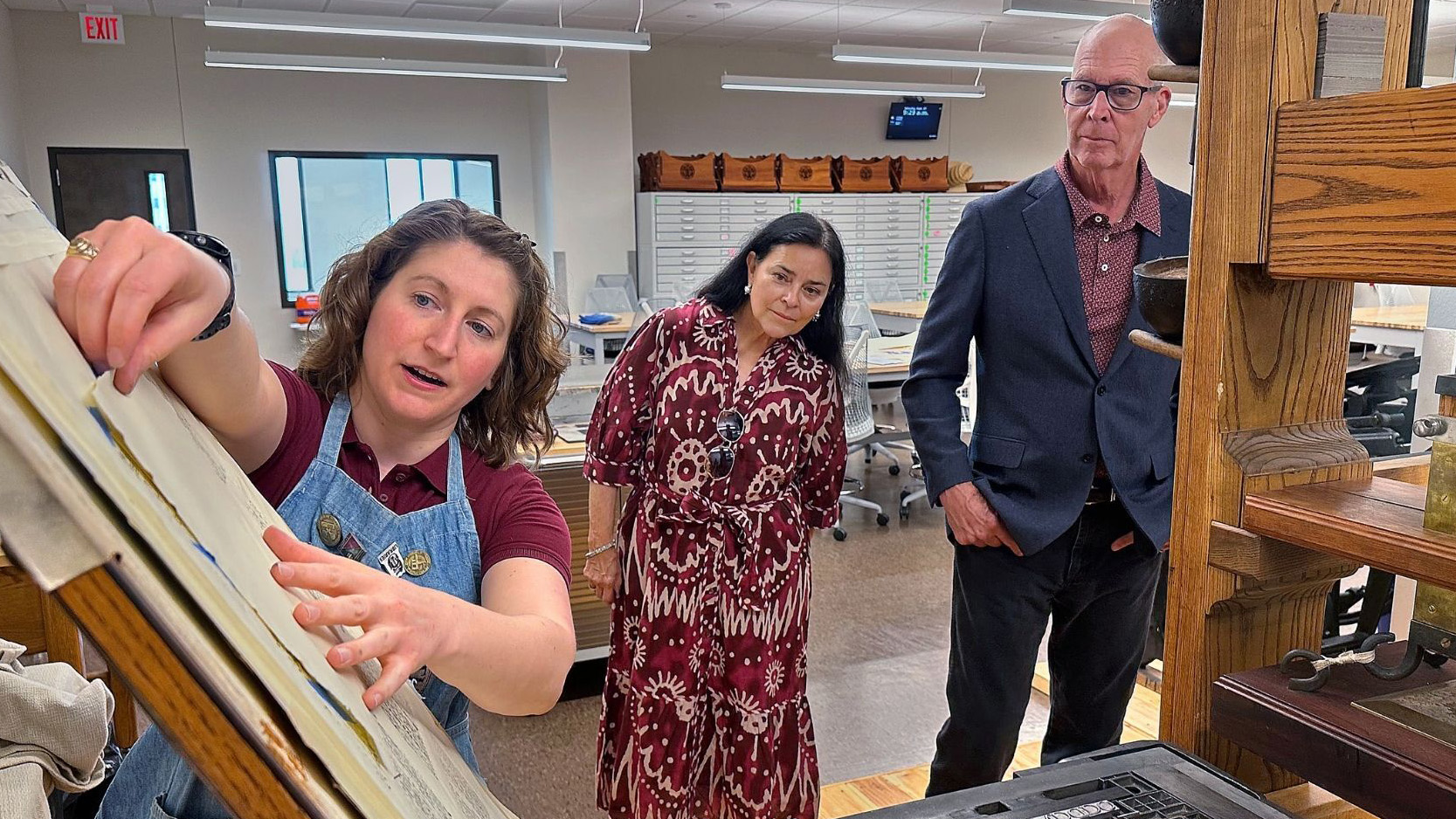Maddie Keyser, Texas A&M University’s book arts and historic press room librarian, shows a period accurate common press in the Sterling C. Evans Library Annex to Dr. Diana Gabaldon and her husband, Doug Watkins.